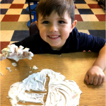 K student write letter F in cream with big smile